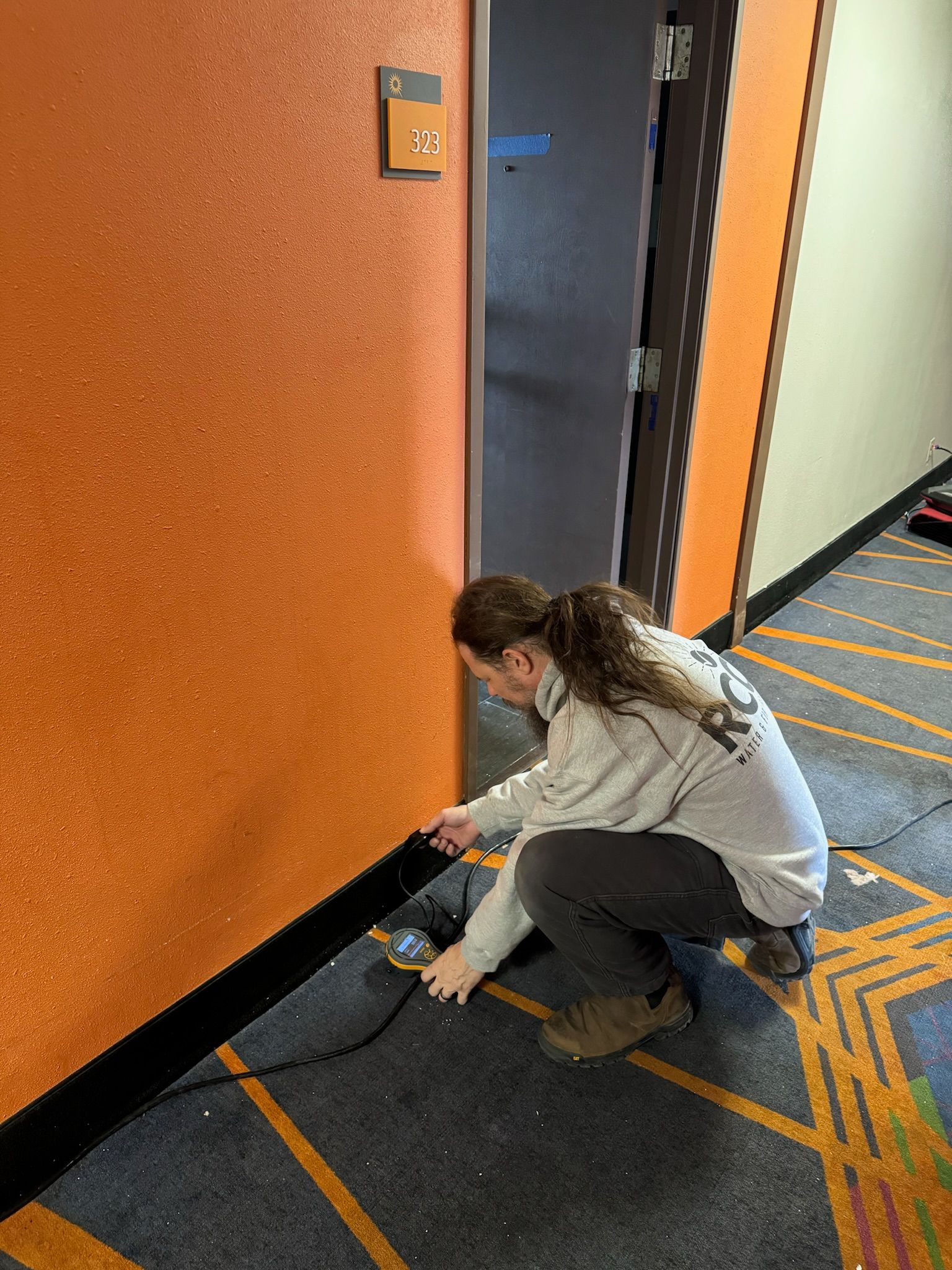 A woman is kneeling down in a hallway next to a door.