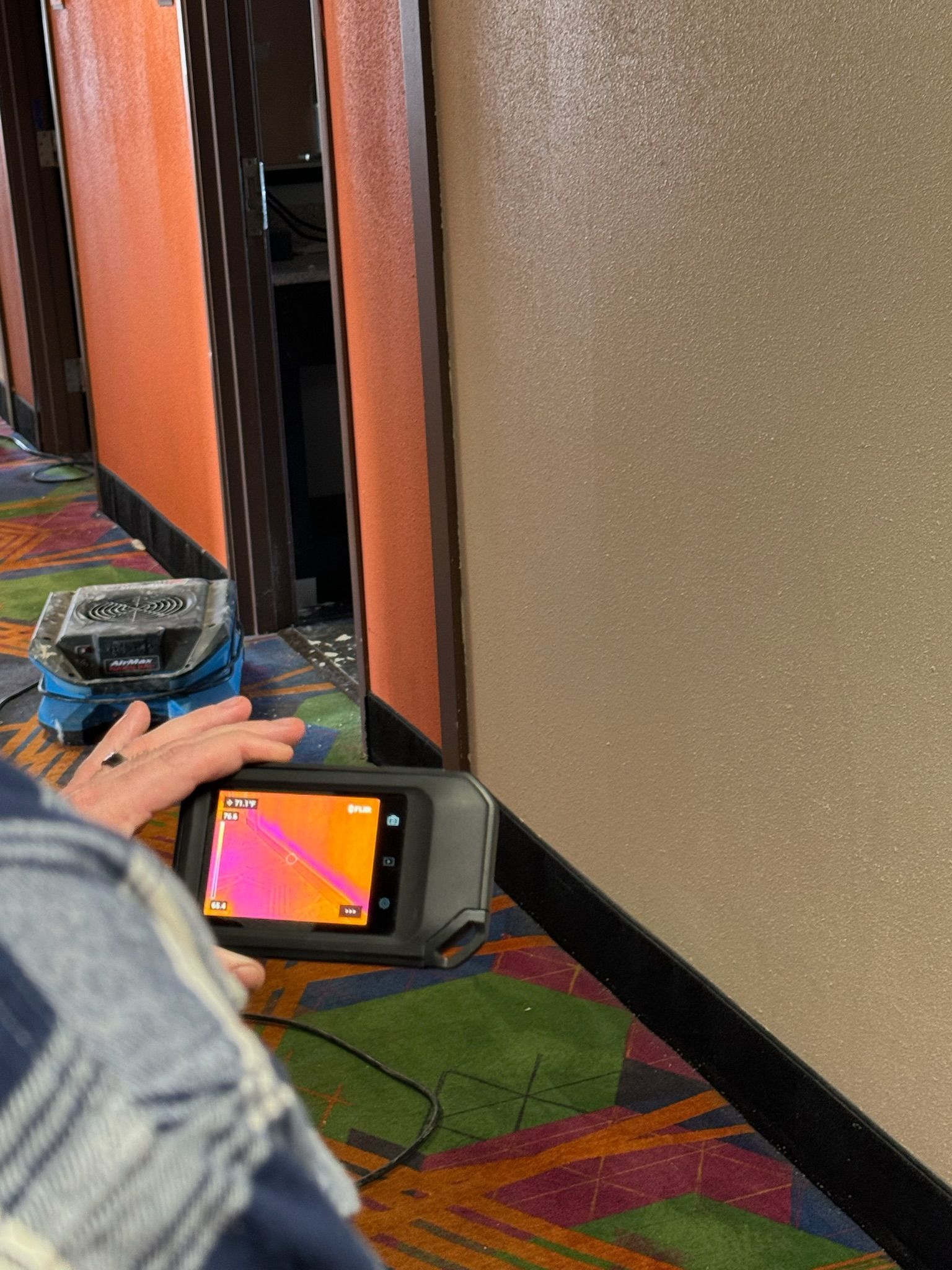 A person is taking a picture of a wall with a thermal camera.