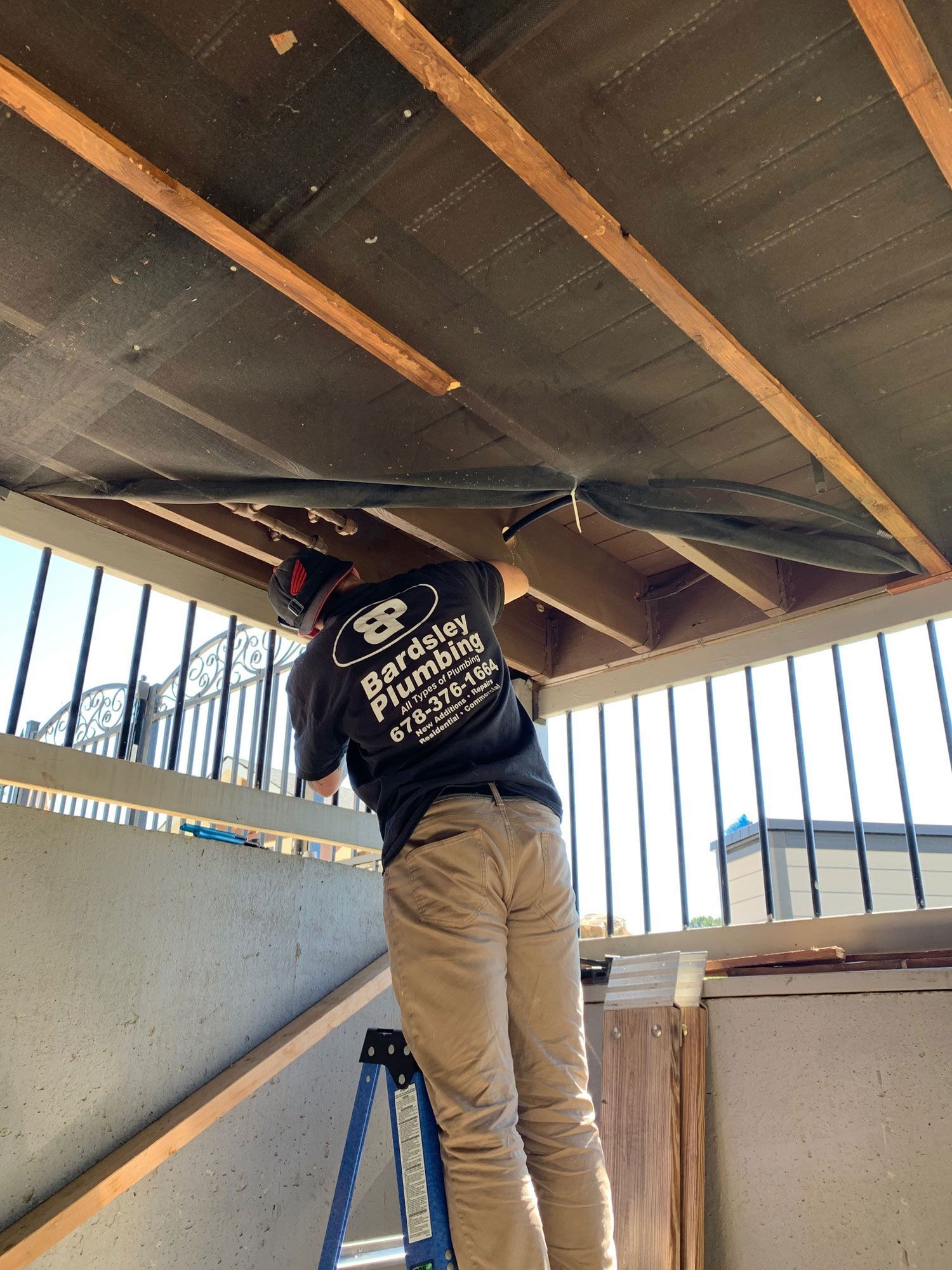 a man is standing on a ladder working on whole house Water re-piping.