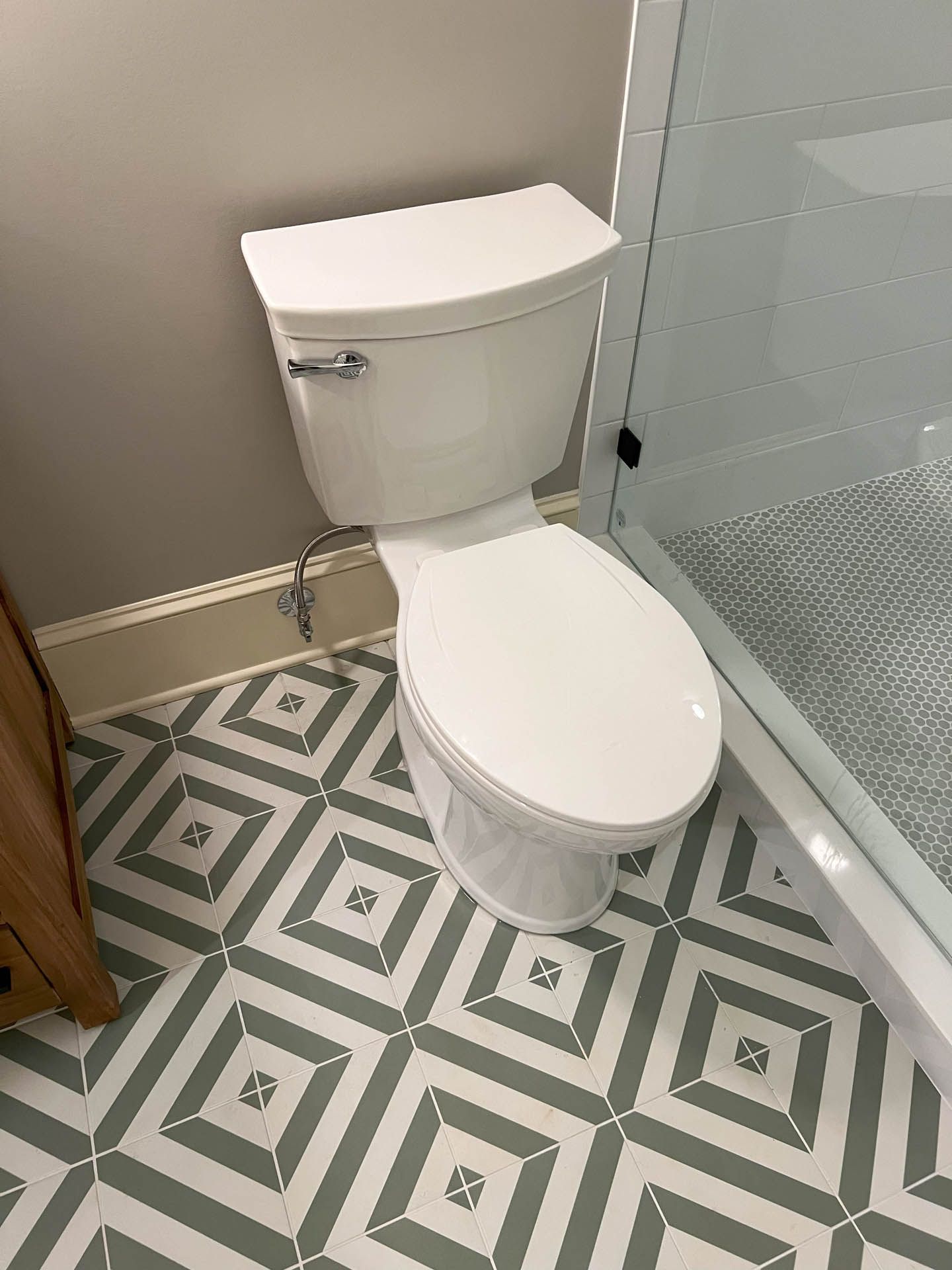 A toilet is sitting on a tiled floor in a bathroom next to a shower.