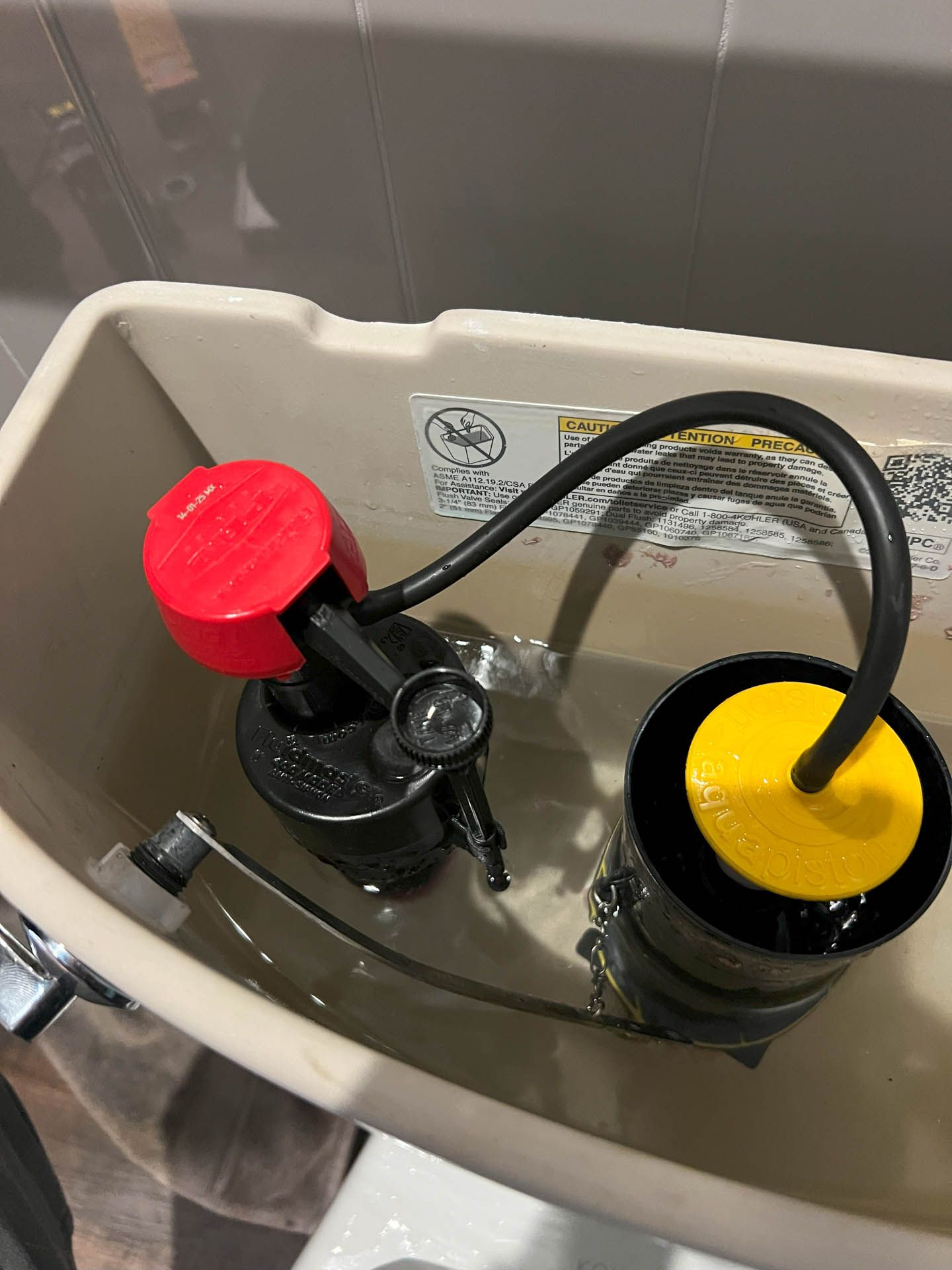 A close up of a toilet tank with a yellow cap on it.