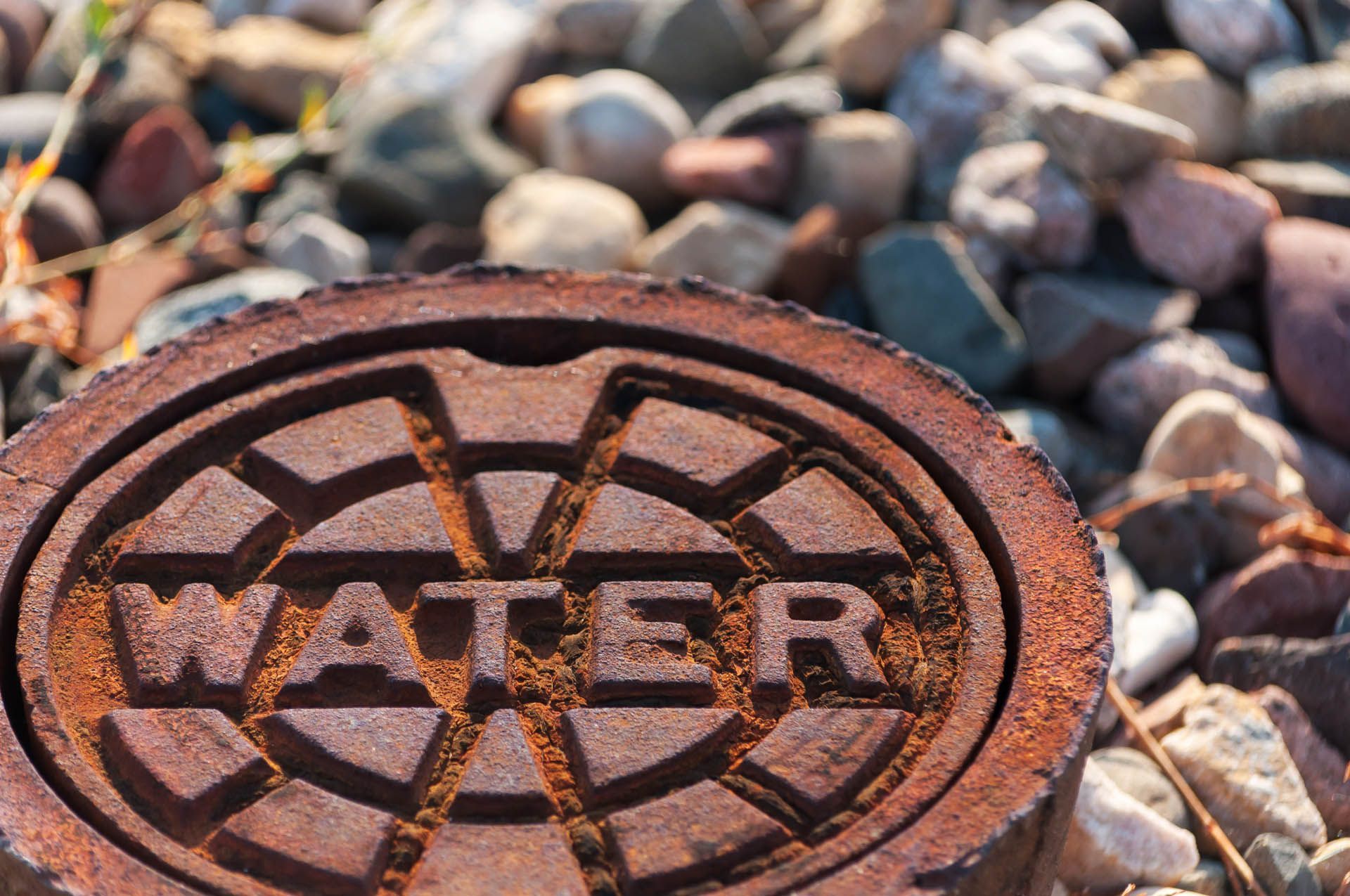 a rusty water main cover with the word water written on it
