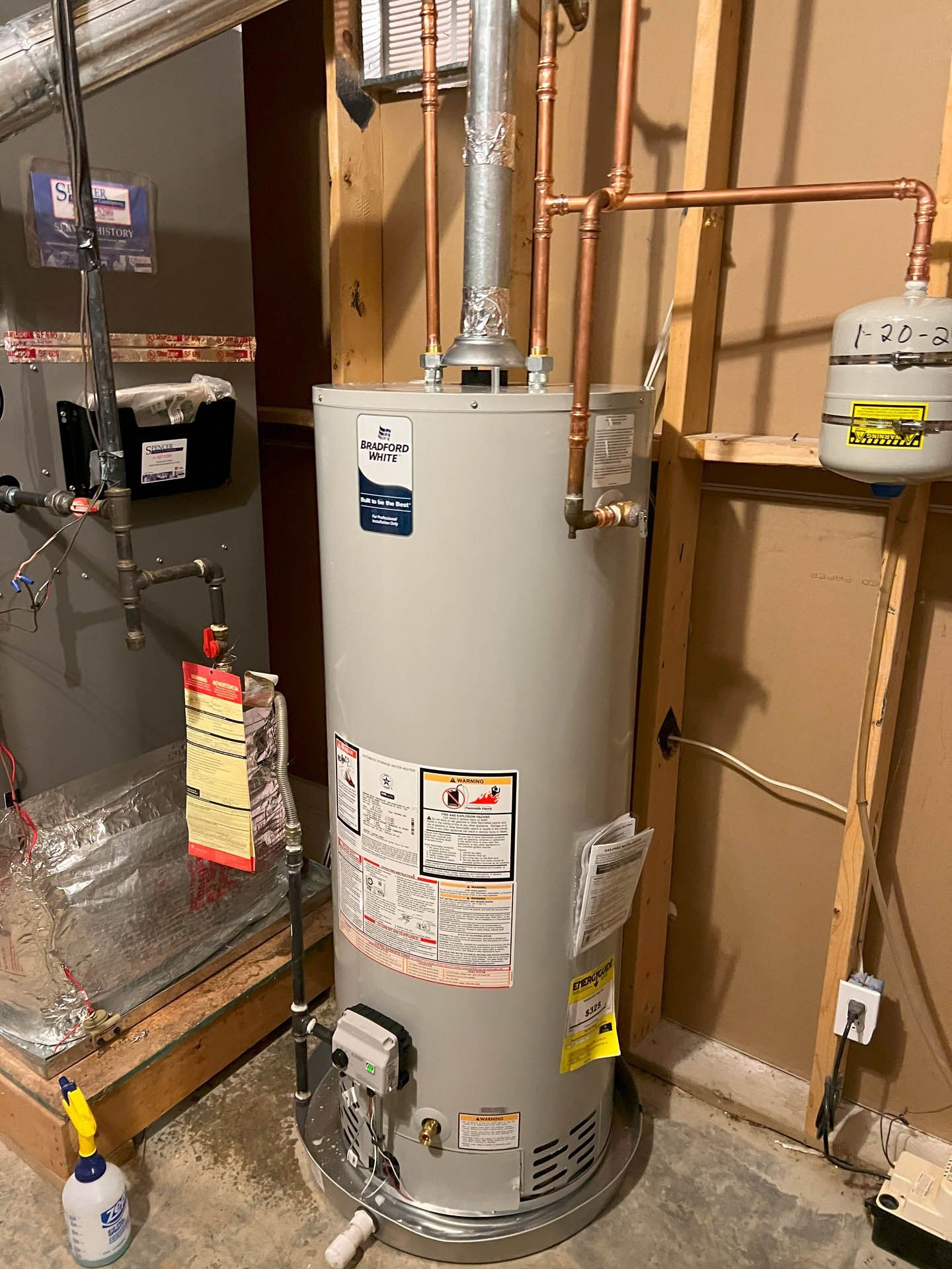 A water heater is sitting in a basement next to a wall.