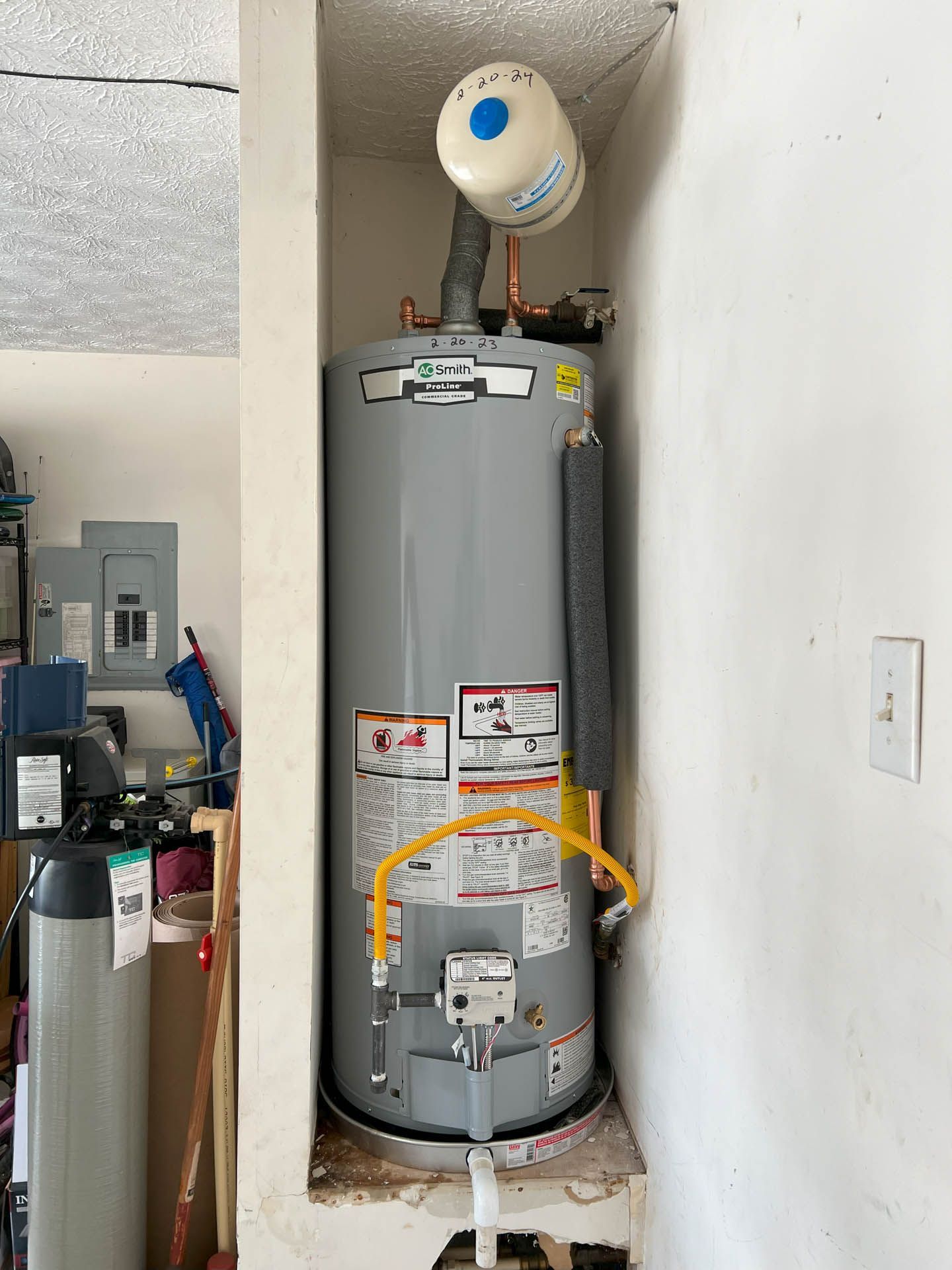 A water heater is sitting in a corner of a room.