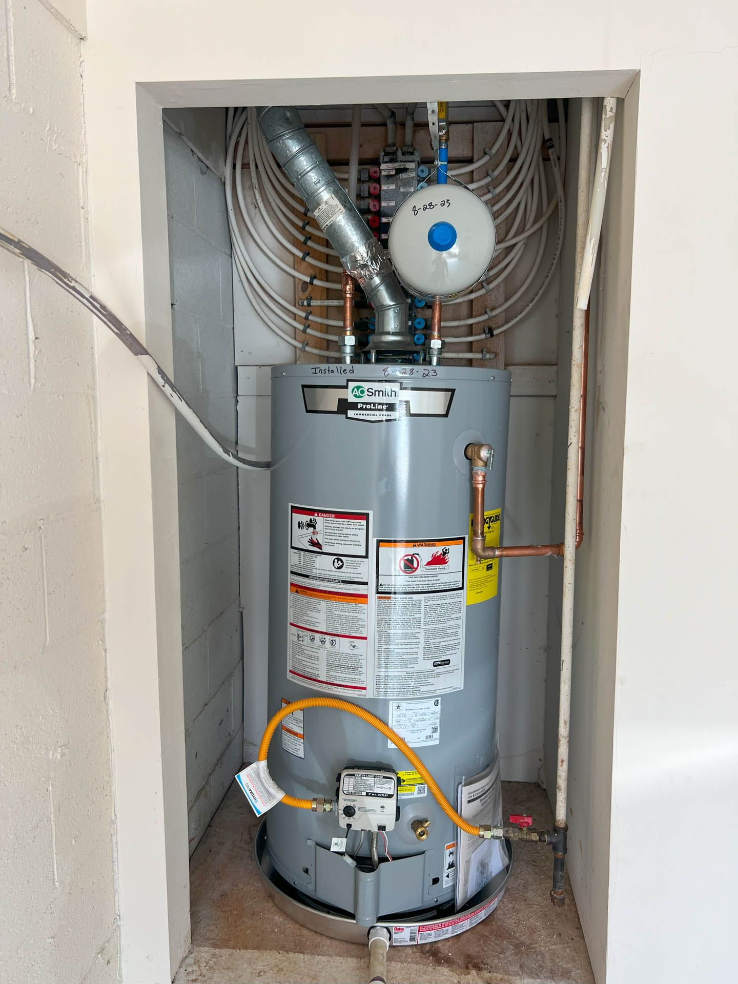 A water heater is sitting in a corner of a room.