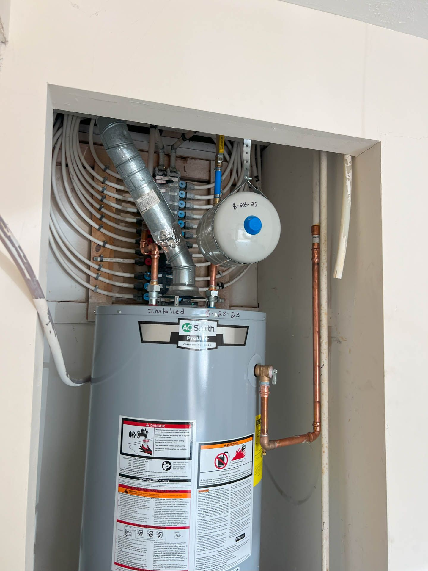 A water heater is sitting in a closet next to a wall.