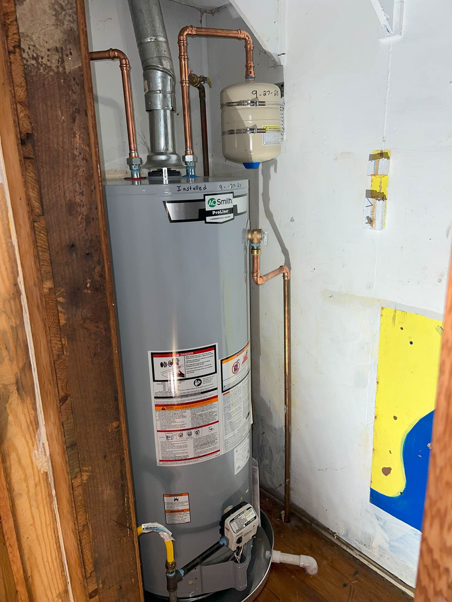 A water heater is sitting in a room next to a wall.