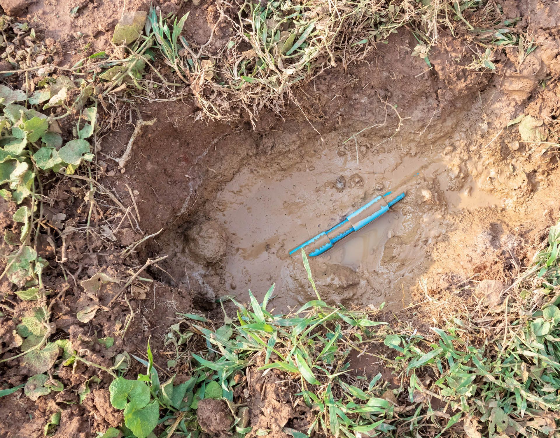 a hole in the ground with a blue pen in it .
