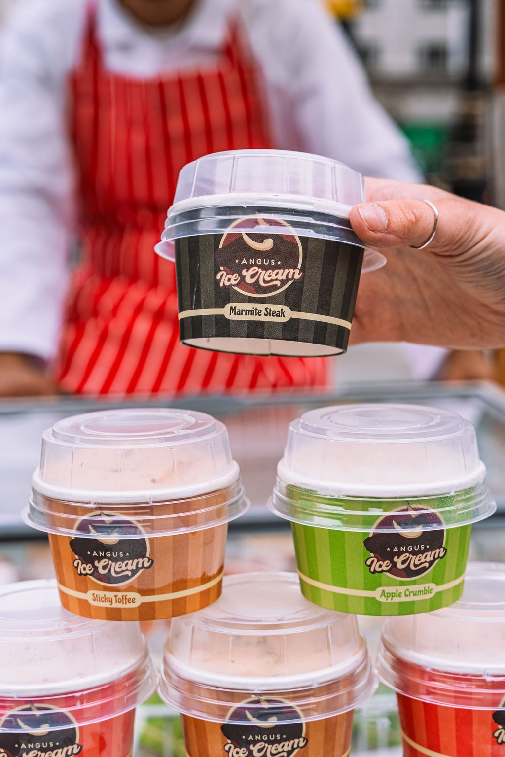 A person is holding a cup of ice cream in front of a counter.