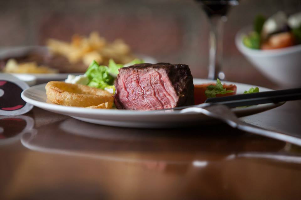 A plate of food with a steak and french fries on a table.