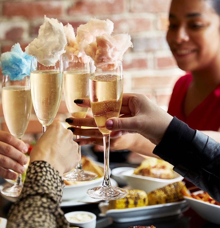 A group of people are toasting with champagne glasses filled with cotton candy.