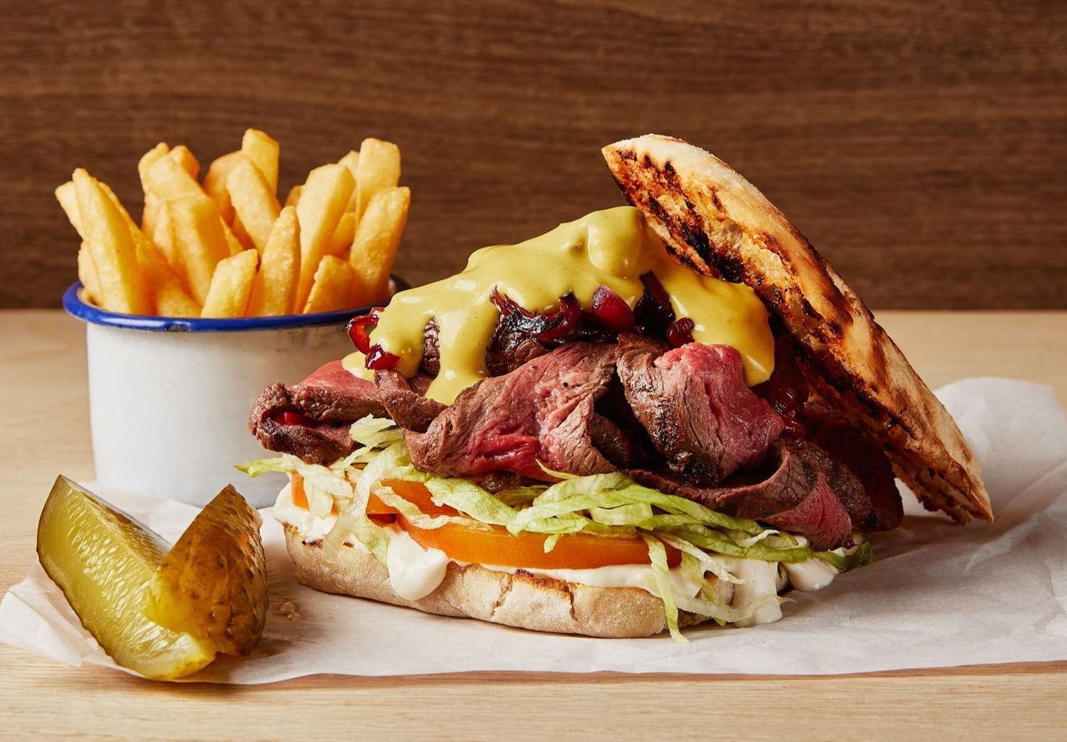 A sandwich with a pickle and french fries on a table.