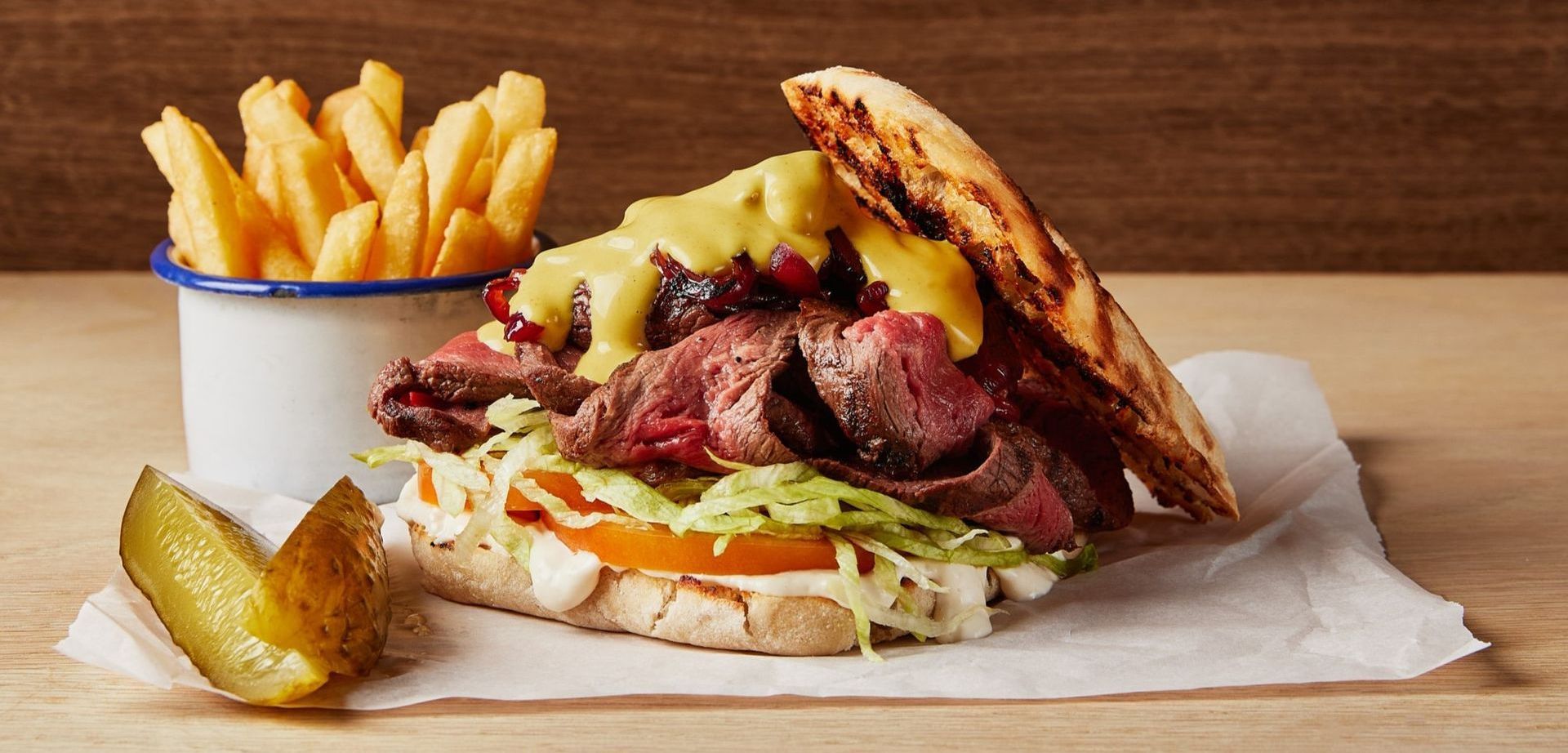 A sandwich with french fries and pickles on a table.