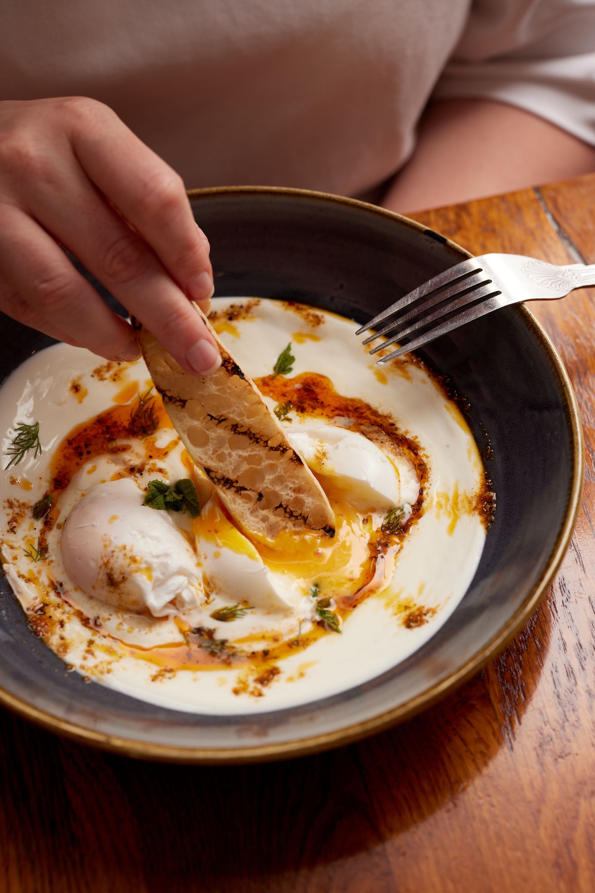 A person is eating a bowl of food with a fork.