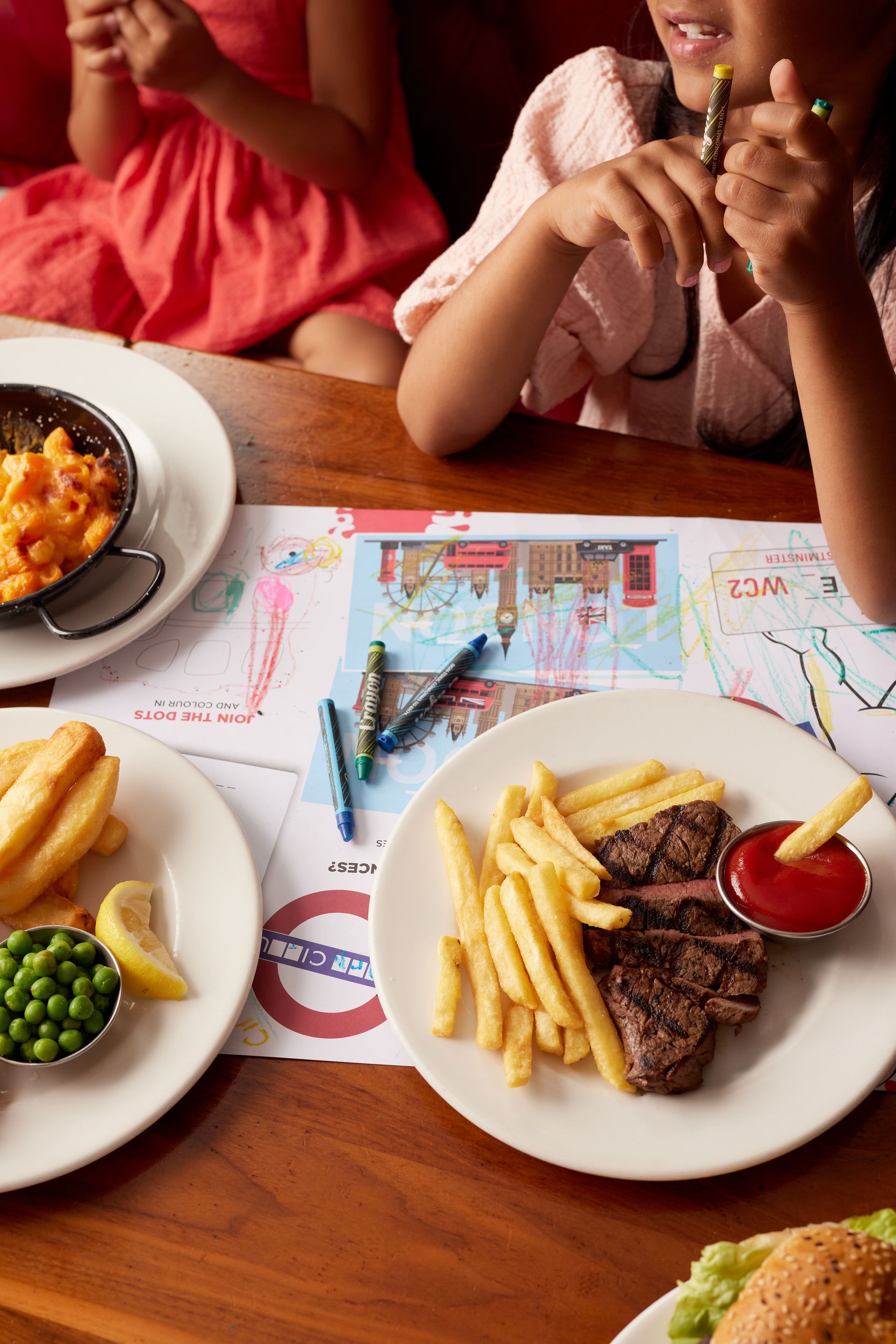 A group of children are sitting at a table with plates of food.