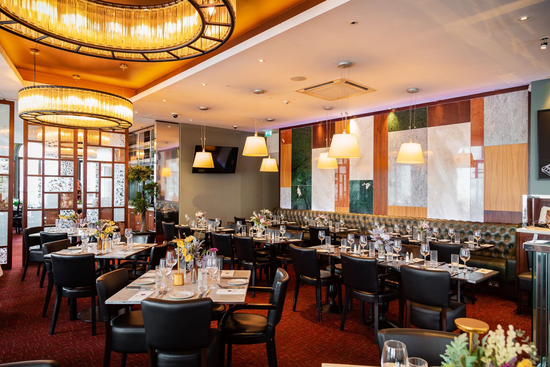 A large dining room with tables and chairs and a chandelier hanging from the ceiling.