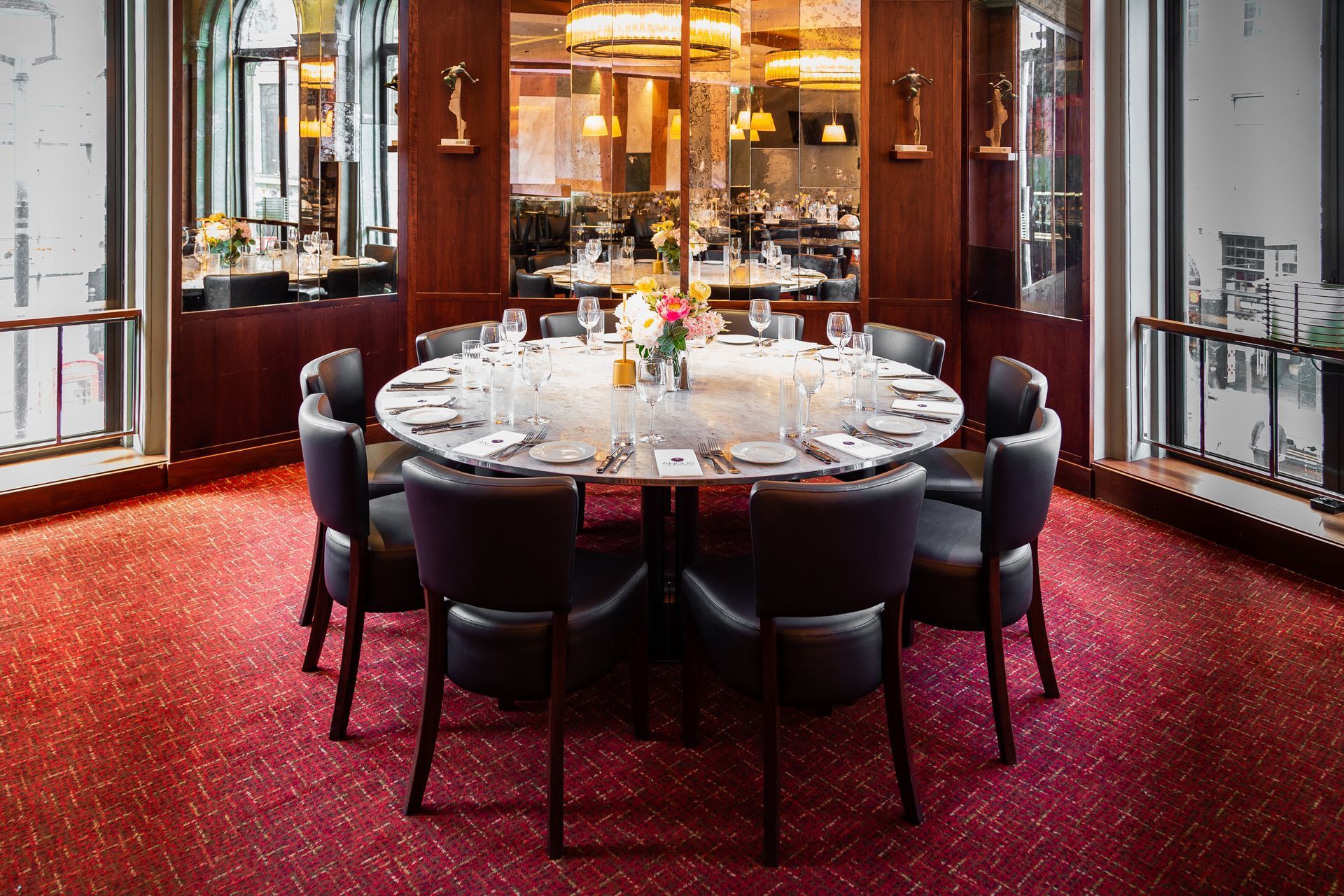 A dining room with a round table and chairs and a red carpet.