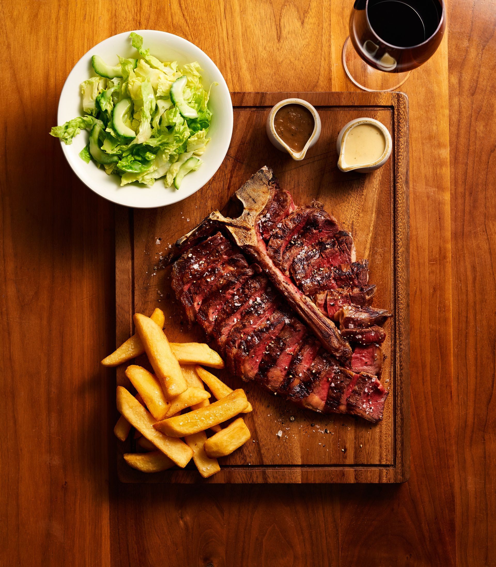 A steak and french fries on a wooden cutting board