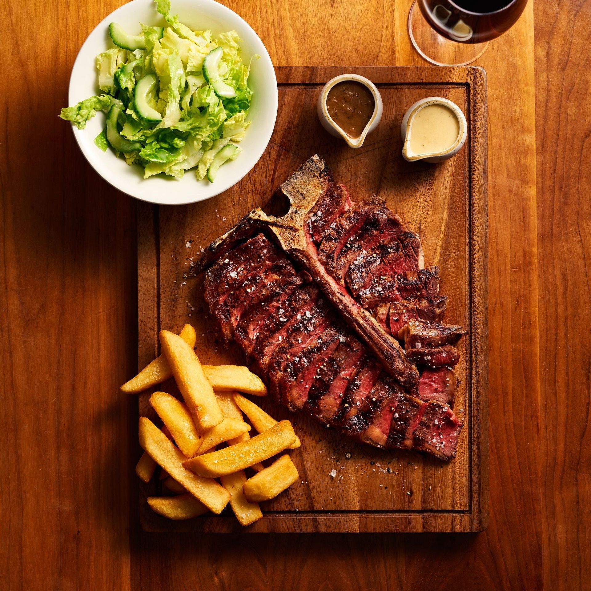 A steak and french fries on a wooden cutting board