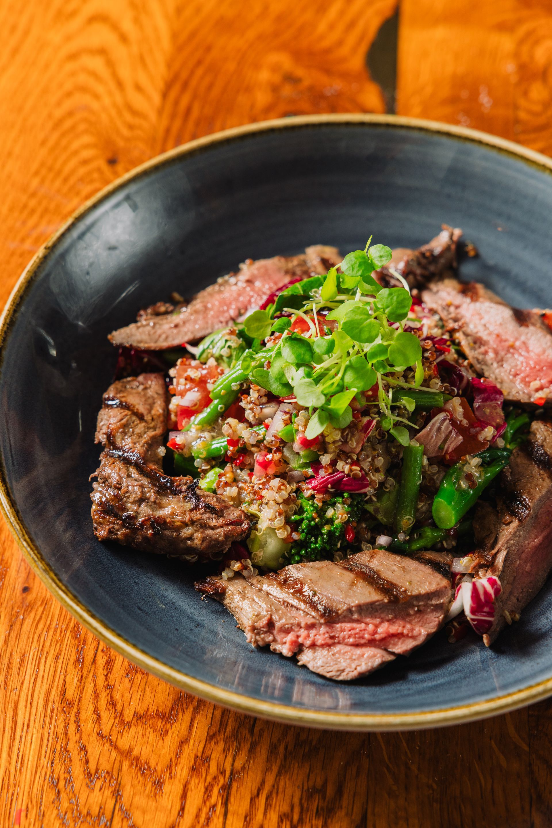 A close up of a plate of food on a wooden table.
