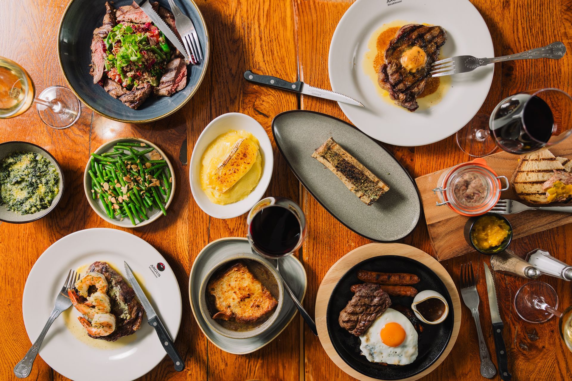 A wooden table topped with plates of food and wine glasses.