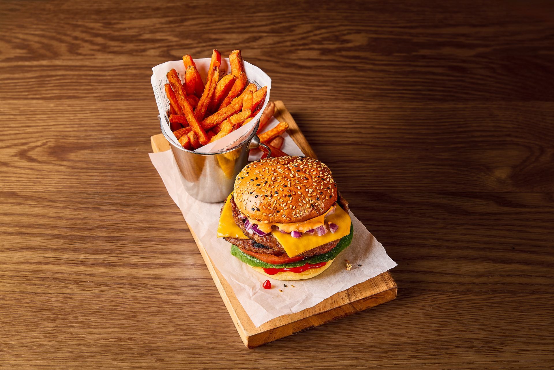 A variety of steaks are sitting on wooden cutting boards on a wooden table.