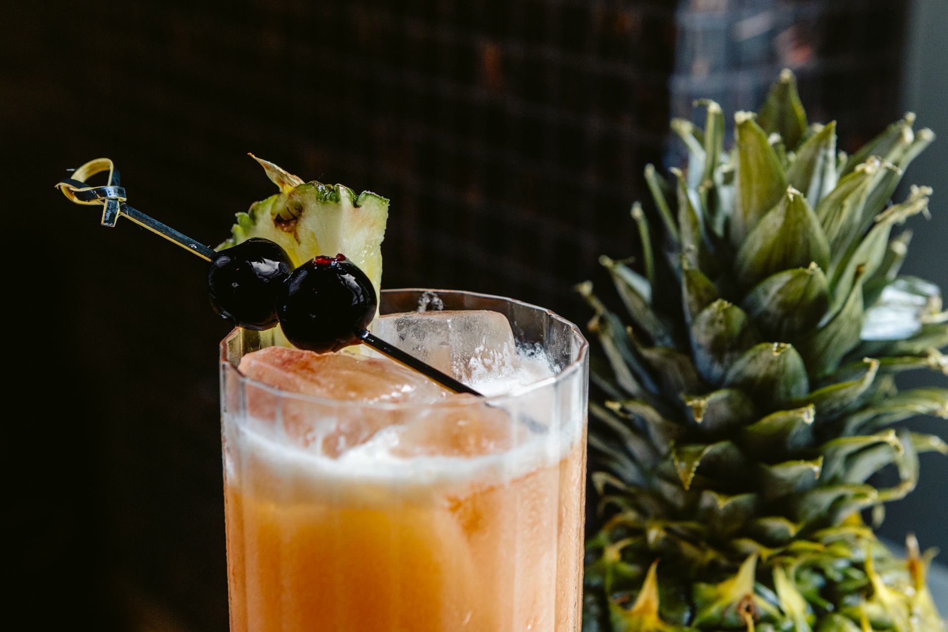 A close up of a cocktail with a pineapple in the background.