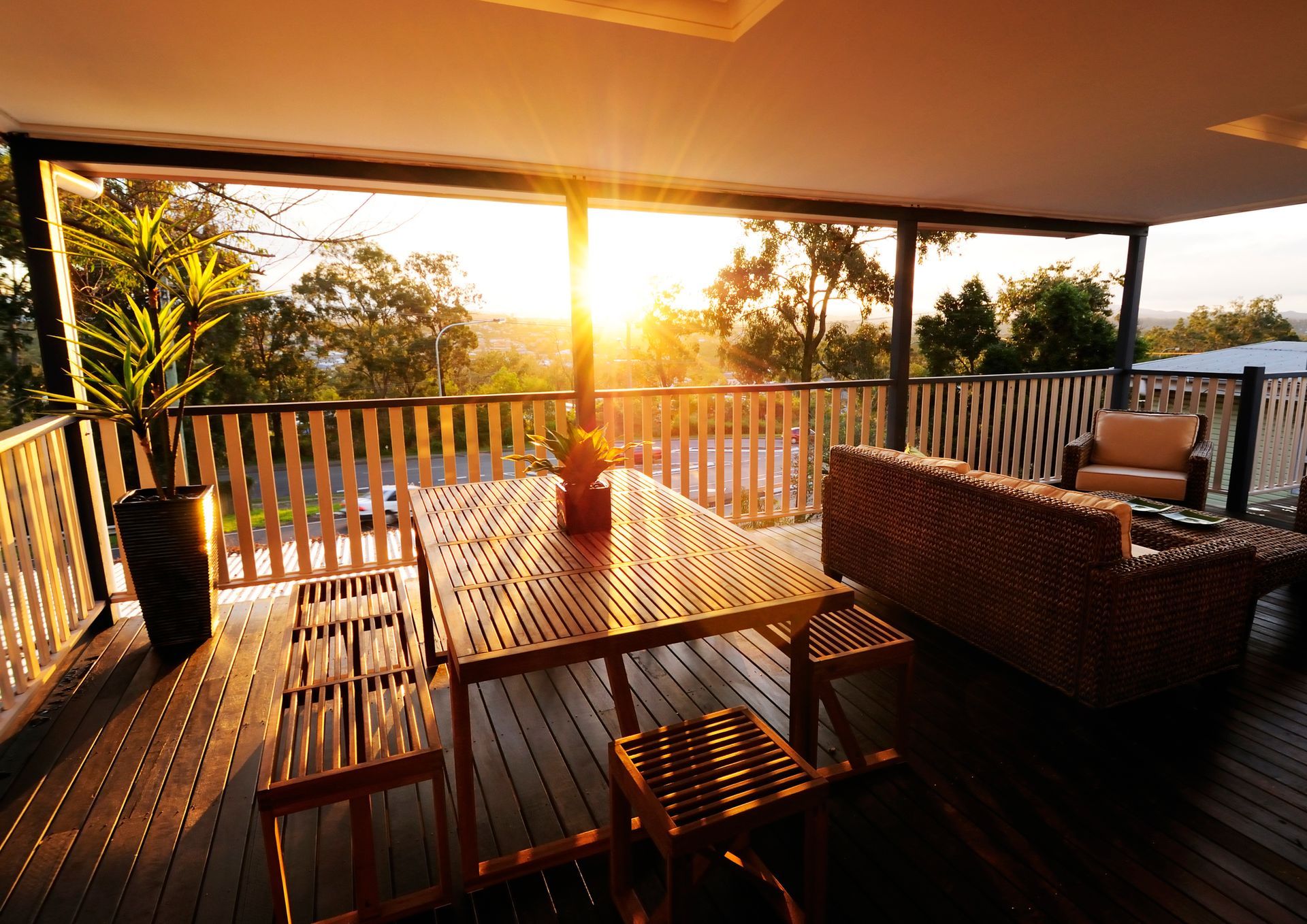 The sun is setting over a deck with a table and chairs