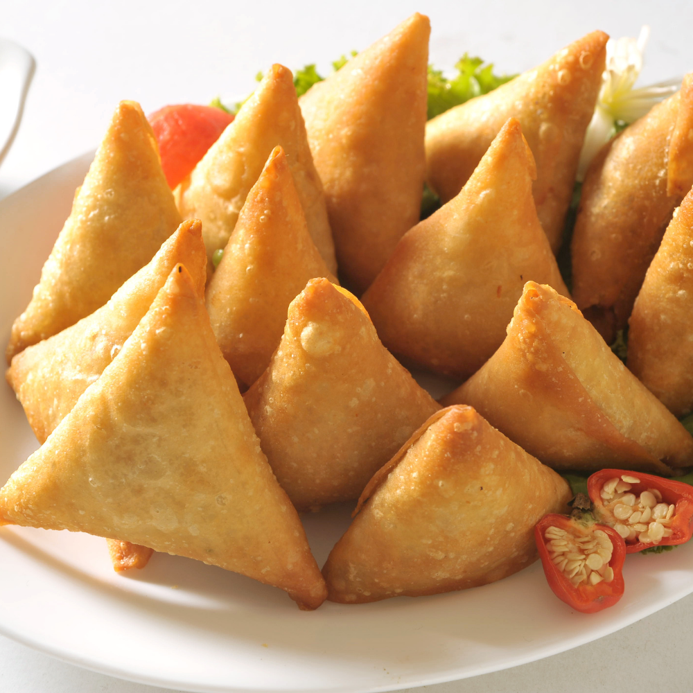 Une assiette blanche garnie de triangles frits et de tomates