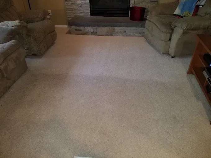 Beige carpet in a living room, with two recliners, a fireplace, and a media console.