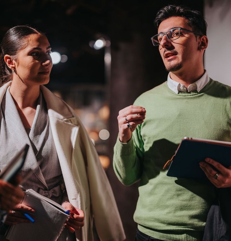 A man in a green sweater is talking to a woman in a white coat