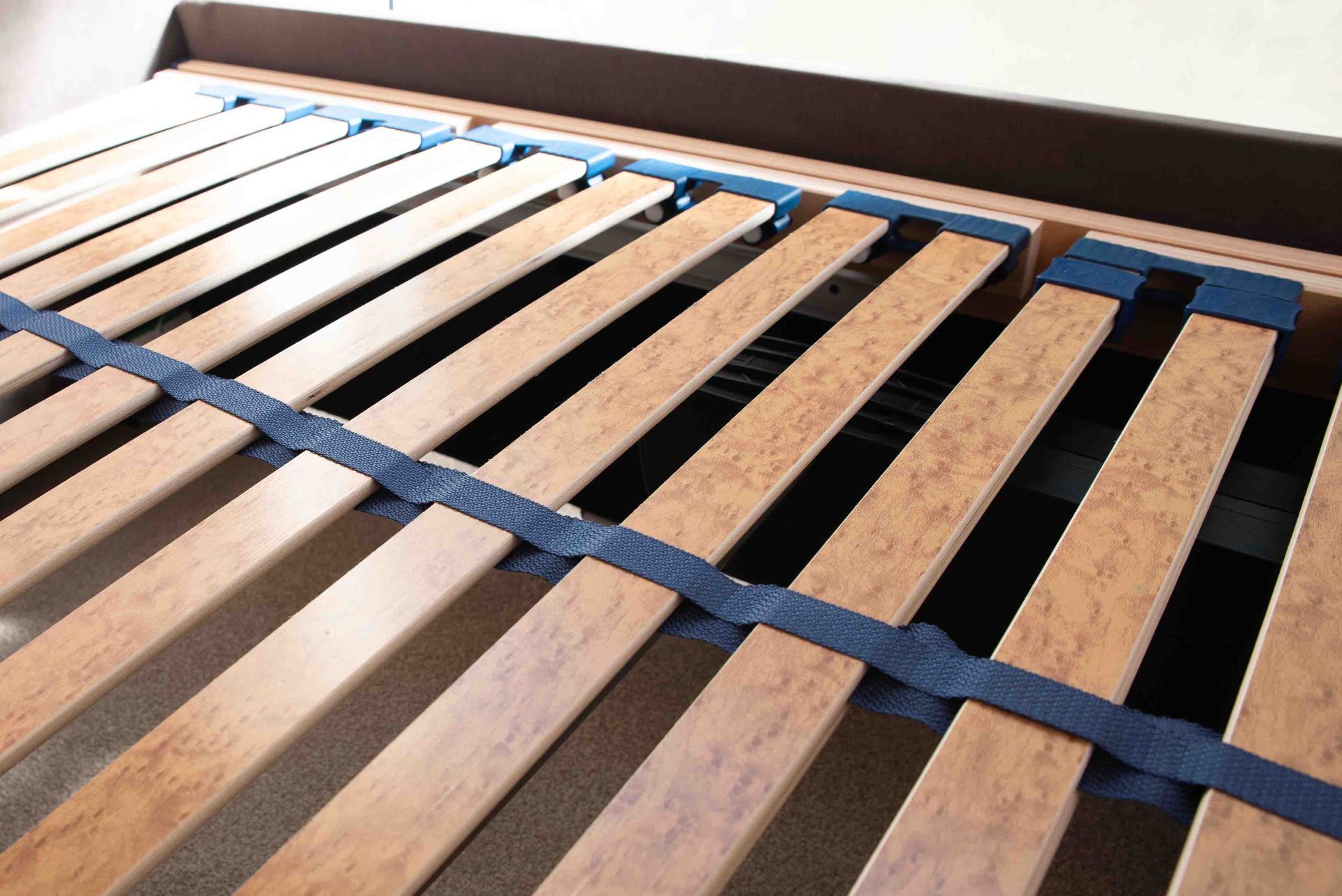 A close up of a wooden bed frame with blue straps