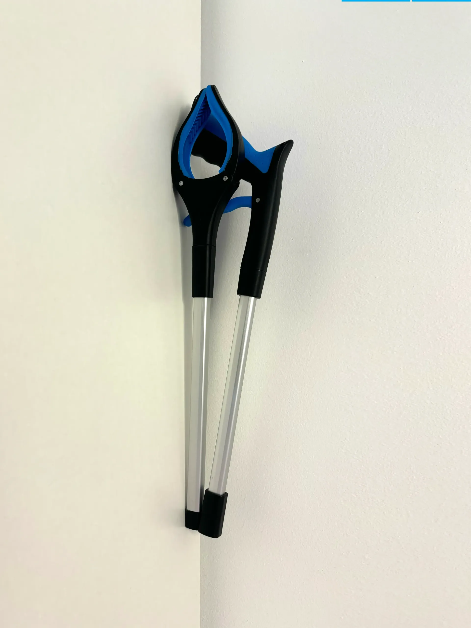 A pair of crutches are hanging on a white wall.