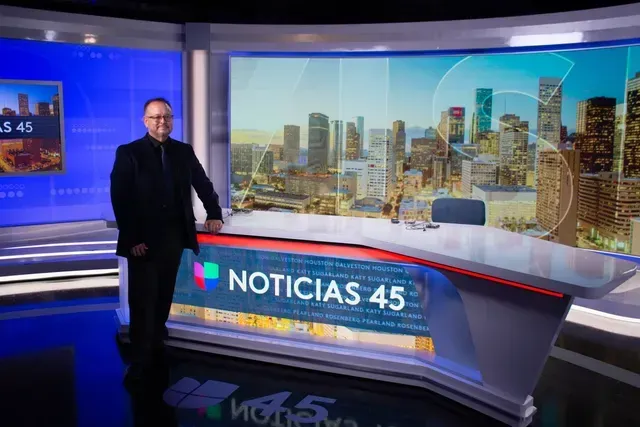 Man standing next to a news desk with 