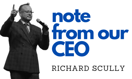 Richard Scully, CEO, giving a presentation with a microphone and raised hand; 