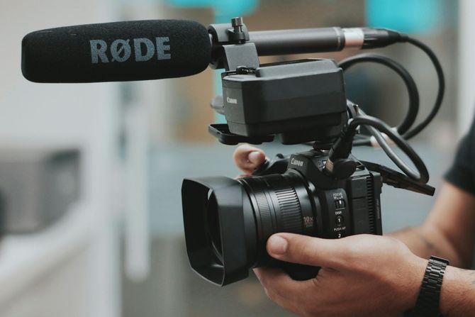 A person is holding a camera with a rode microphone attached to it.