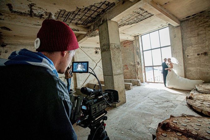 A man is taking a picture of a bride and groom with a camera.