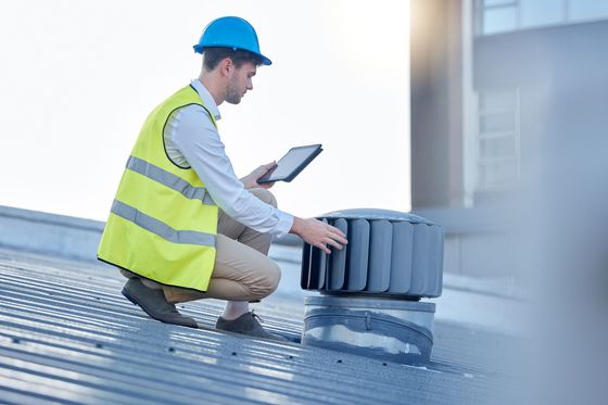 A woman is sitting on the roof of a van using a laptop.