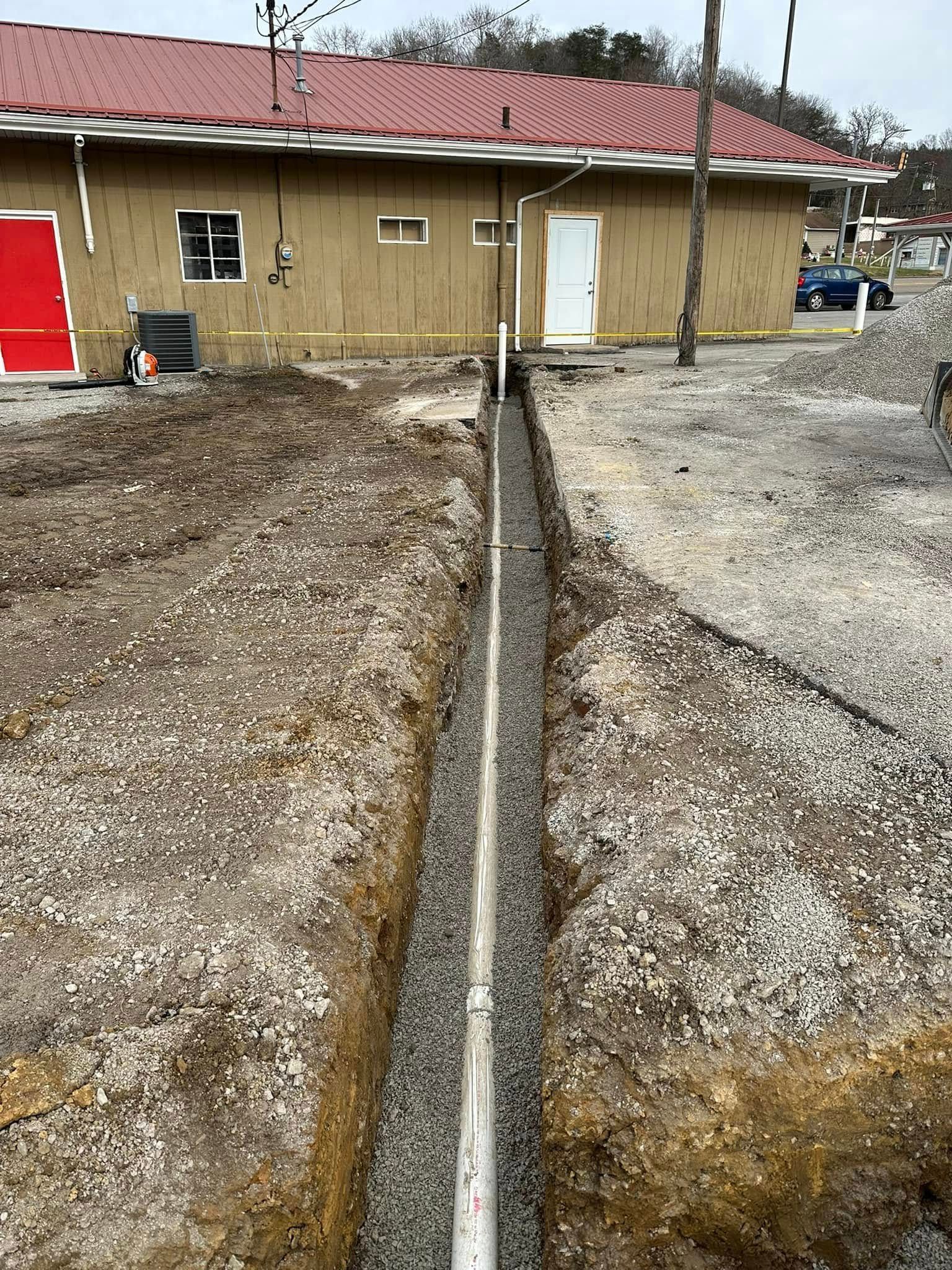 A hose is being installed in the dirt next to a house.