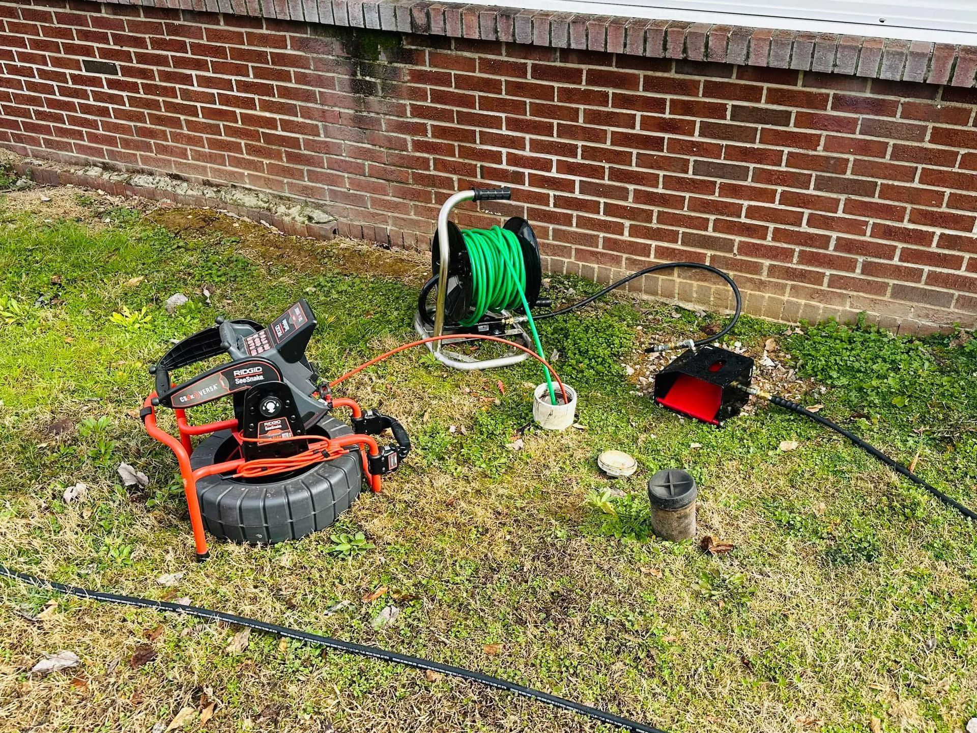A drain camera is sitting on the floor next to a hole in the floor.