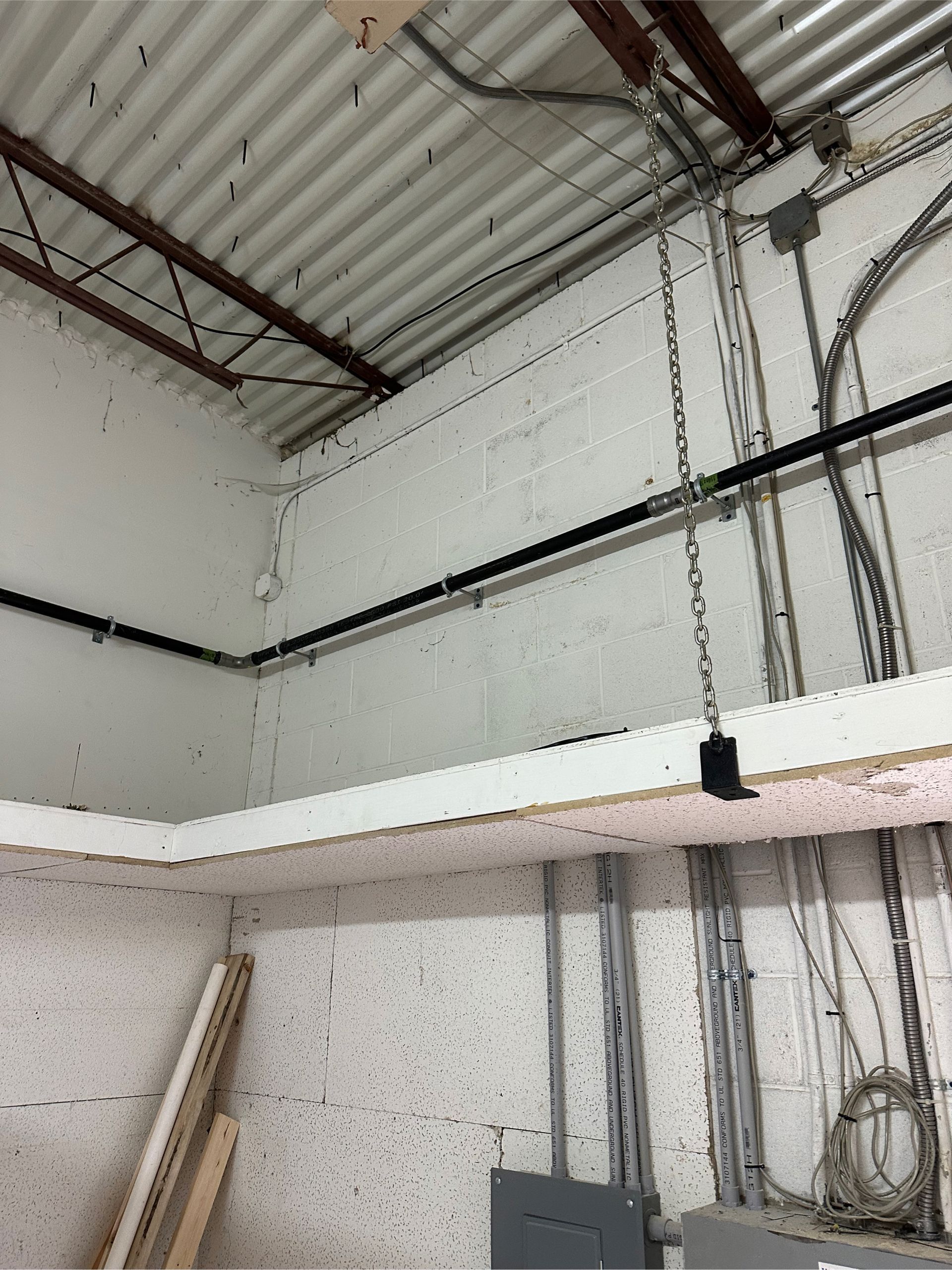 A water heater is sitting in a basement next to a brick wall.