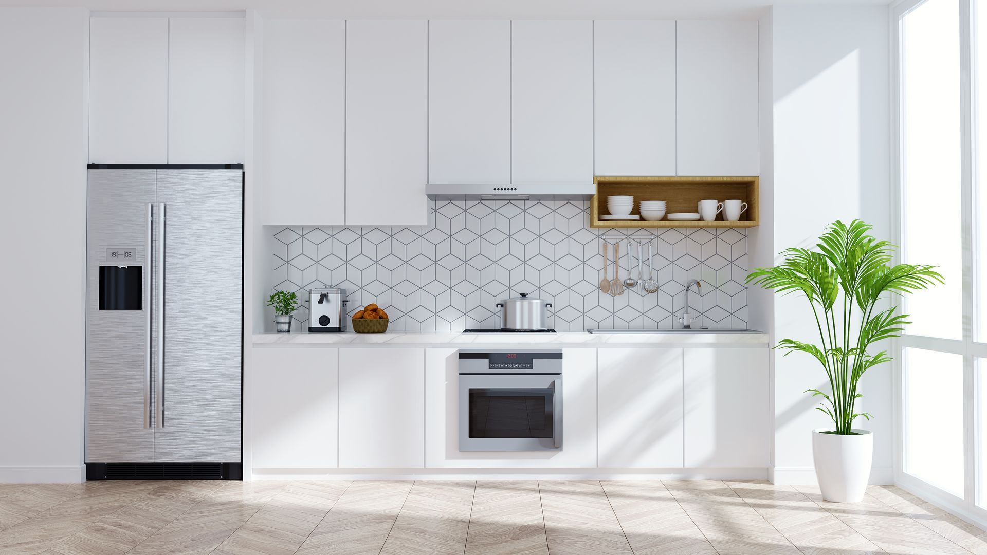 A modern kitchen featuring white cabinets, a stainless steel refrigerator, a built-in oven, and a green potted plant.