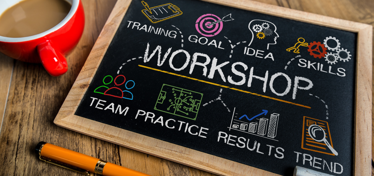 A blackboard with the word workshop written on it next to a cup of coffee.