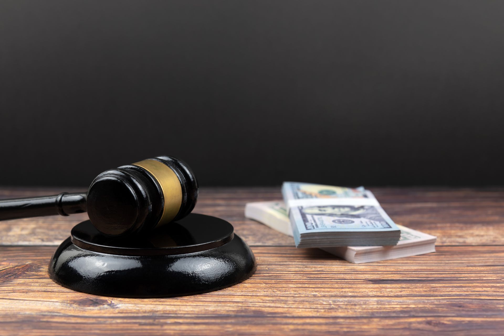 A judge 's gavel is sitting on a wooden table next to a stack of money.