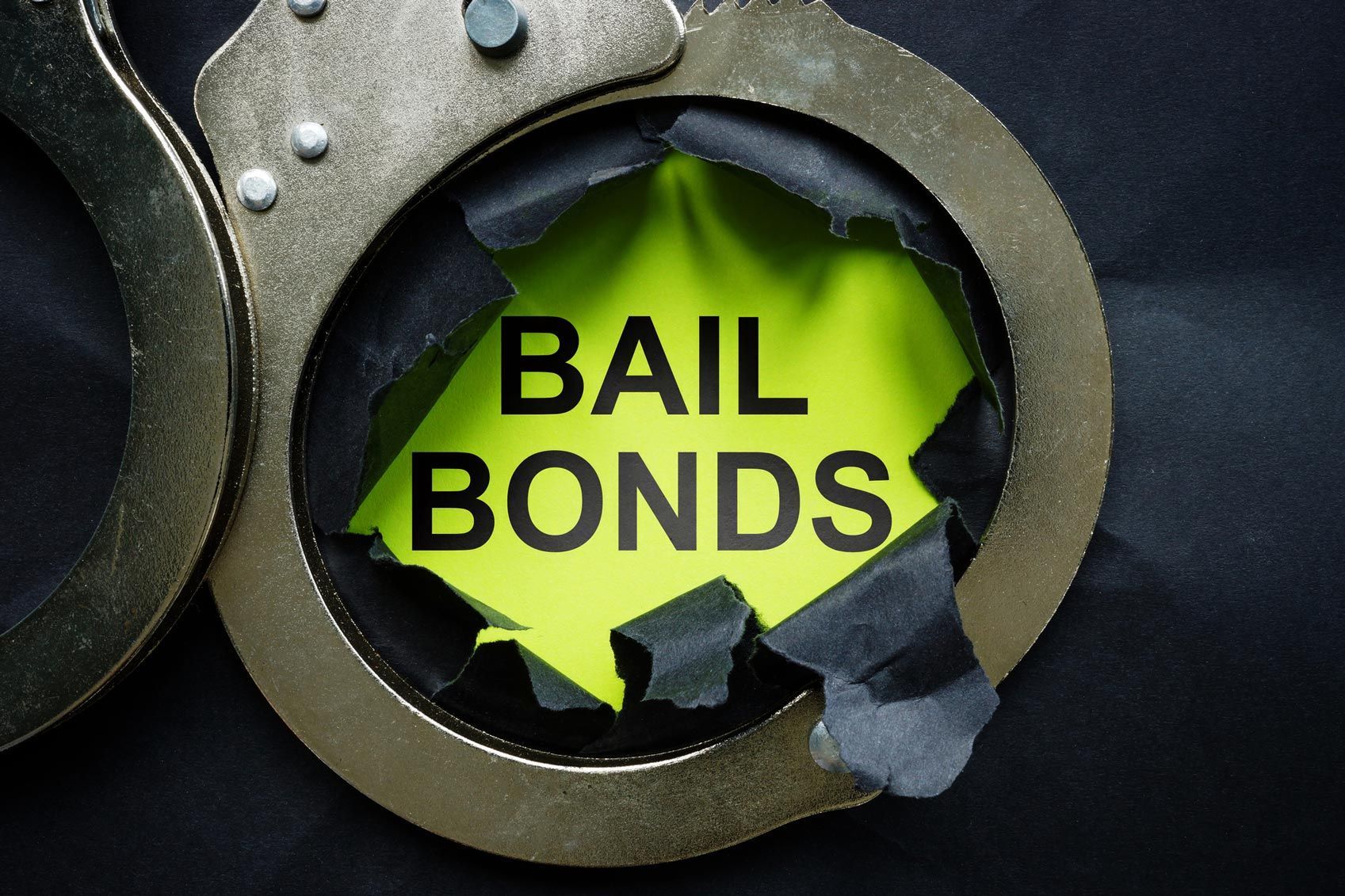 Handcuffs around torn paper showing bold text “BAIL BONDS”. Handcuffs around torn paper showing bold text “BAIL BONDS”.