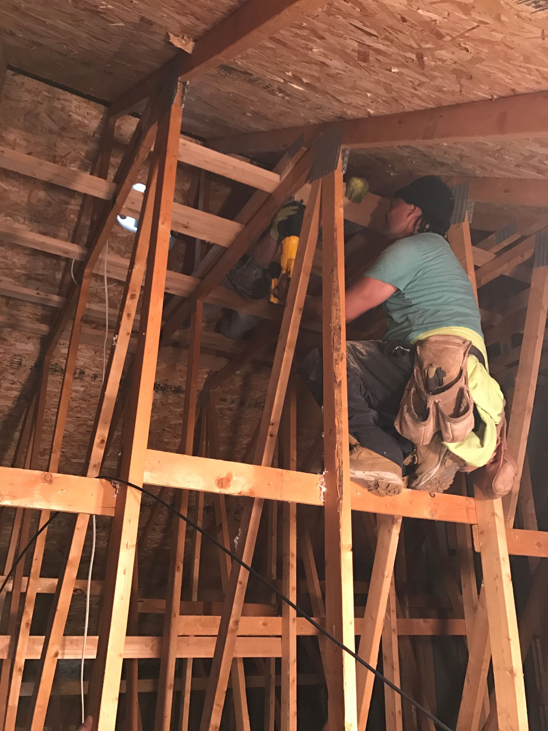 A man in a green shirt is working on a wooden structure