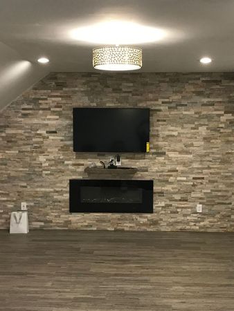A living room with a fireplace and a flat screen tv on the wall.