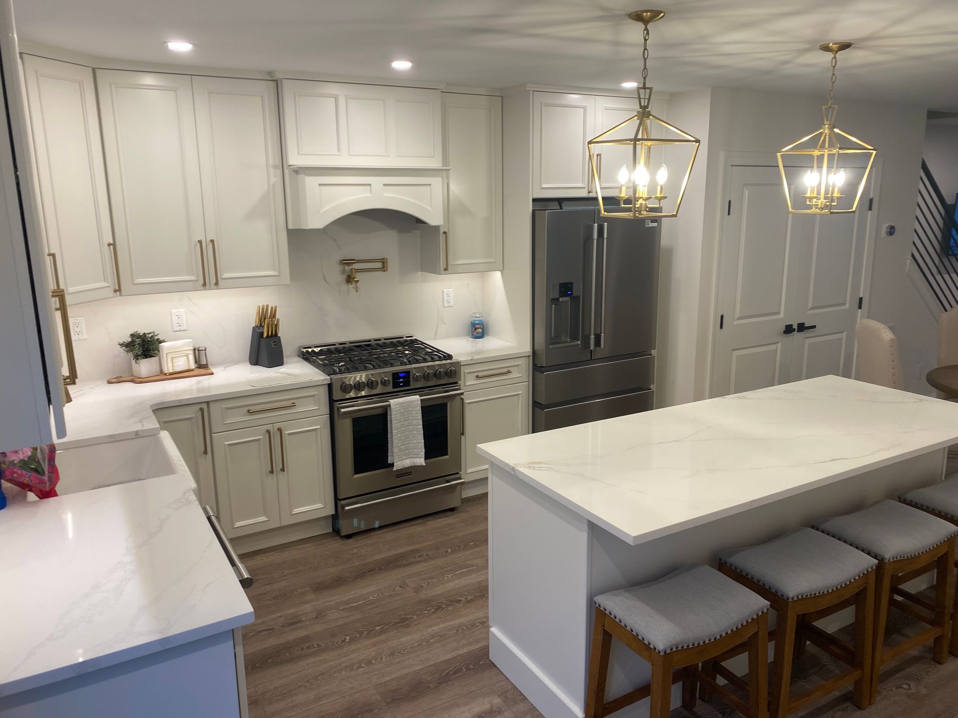 A kitchen with white cabinets , stainless steel appliances , and a large island.