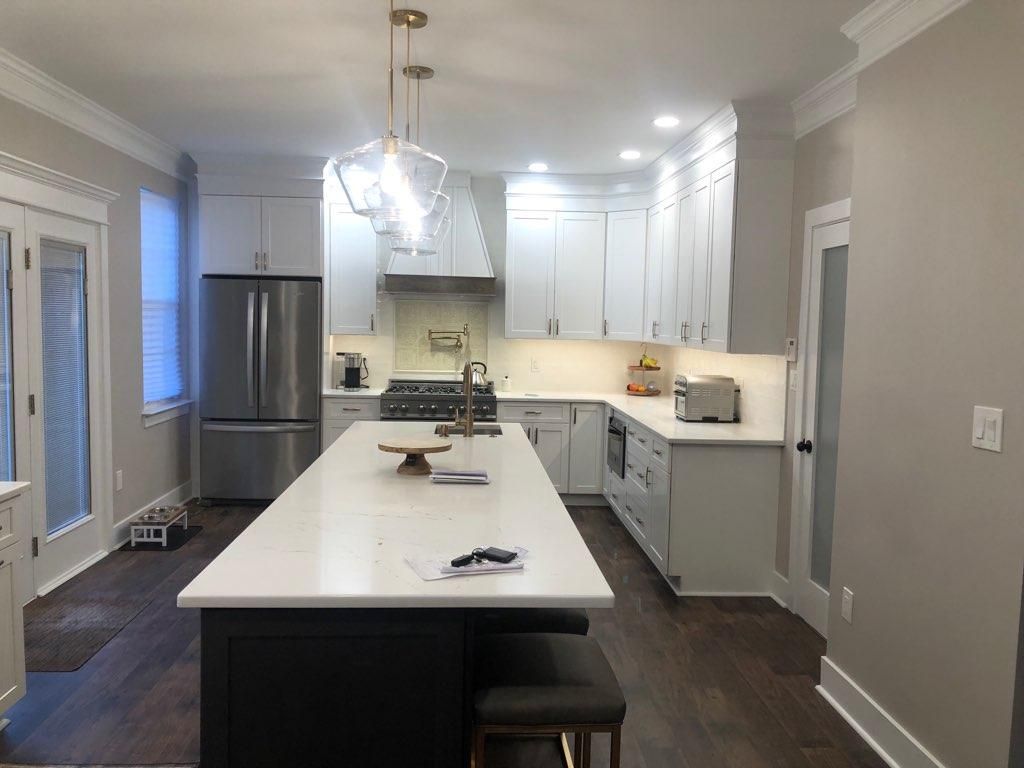 A kitchen with white cabinets , stainless steel appliances , and a large island.
