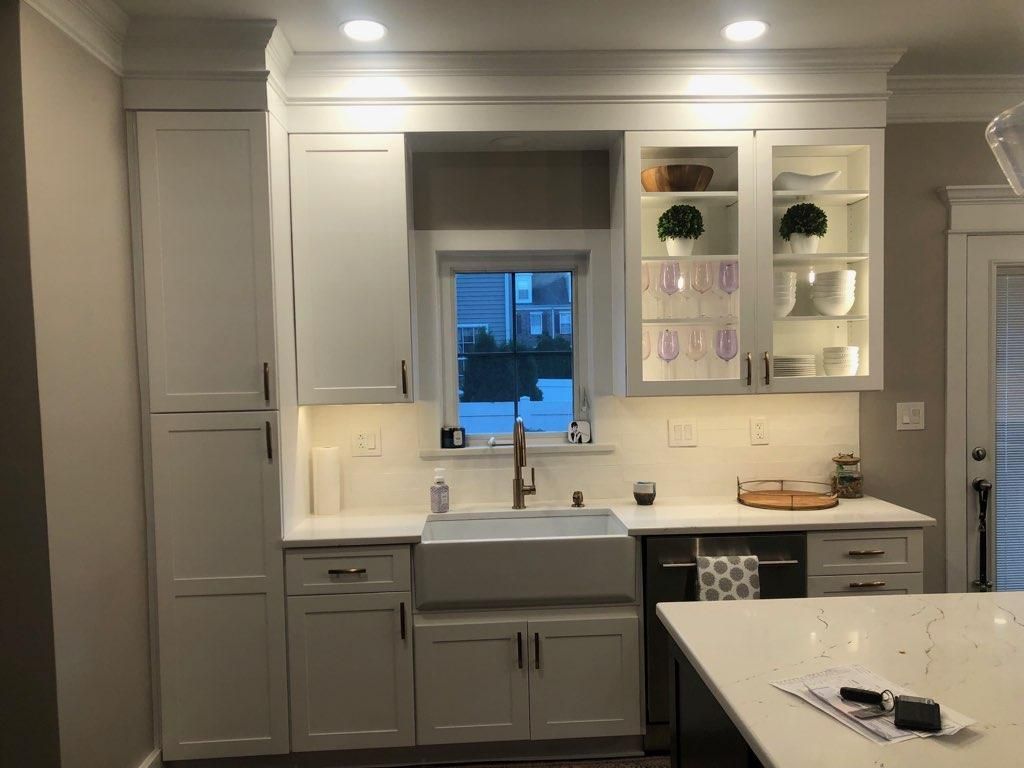 A kitchen with white cabinets , a sink , and a window.
